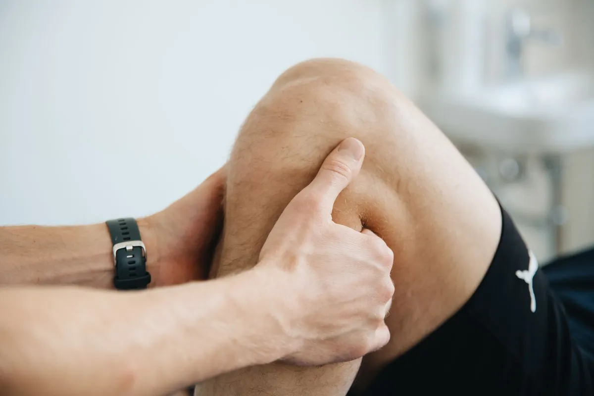 A physiotherapist's hands working on a patient's knee